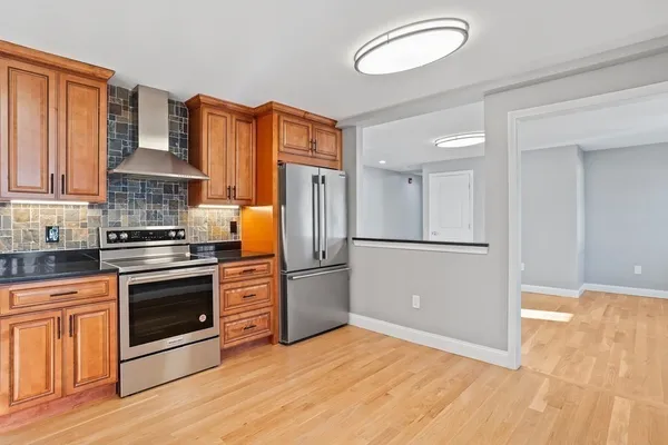 a kitchen with stainless steel appliances granite countertop a refrigerator a stove and a sink