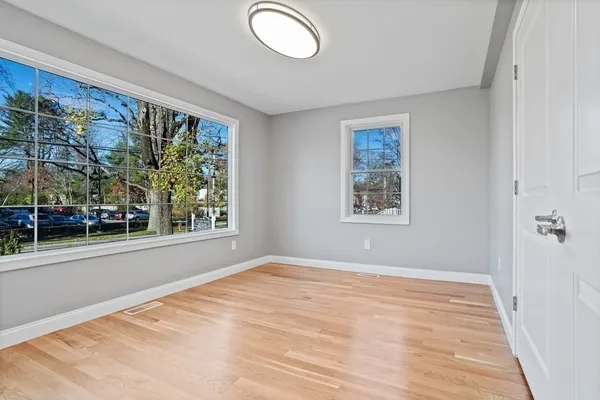 a view of an empty room with a window and wooden floor