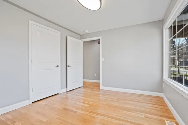 a view of an empty room with wooden floor and a window
