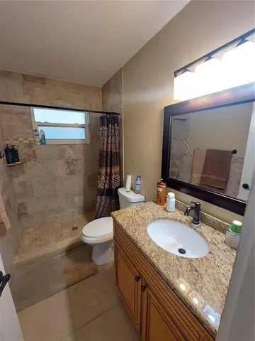 a bathroom with a granite countertop sink toilet and shower