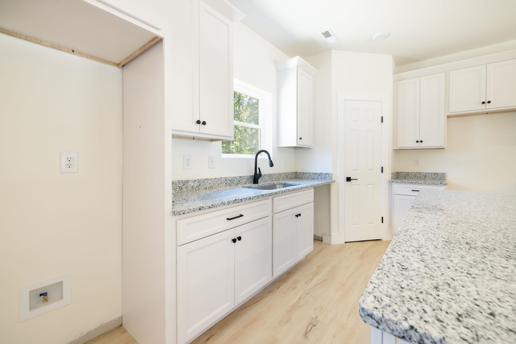 37 William Teague Lane Ramer, TN 38367 - Photo 19 of 39 White cabinetry with black hardware, stone countertops, and wood-finish flooring