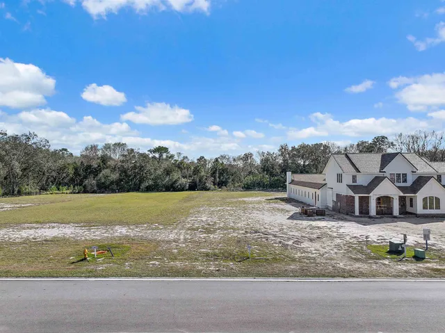 a view of a big house with a big yard and large trees