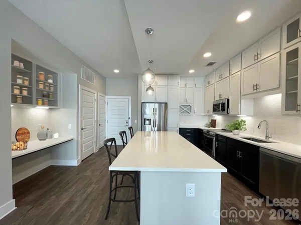 a kitchen with stainless steel appliances sink stove refrigerator and wooden floor