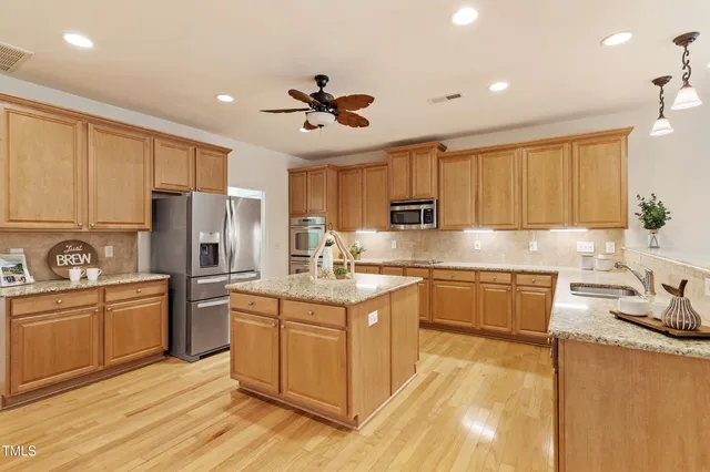 a kitchen with stainless steel appliances granite countertop a sink a stove and a refrigerator