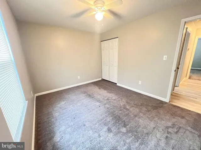 an empty room with a chandelier fan and windows