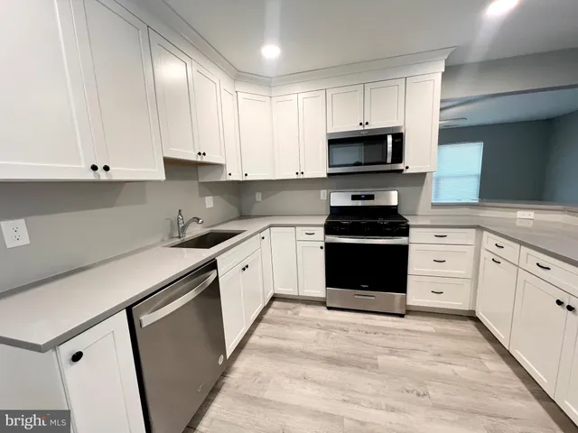 a kitchen with granite countertop white cabinets and stainless steel appliances