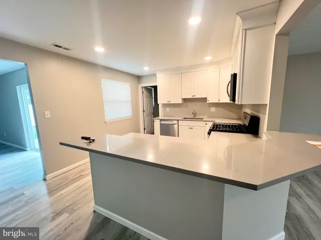 a kitchen with kitchen island a counter top space a sink a refrigerator and a large window