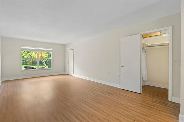 an empty room with wooden floor a ceiling fan and windows