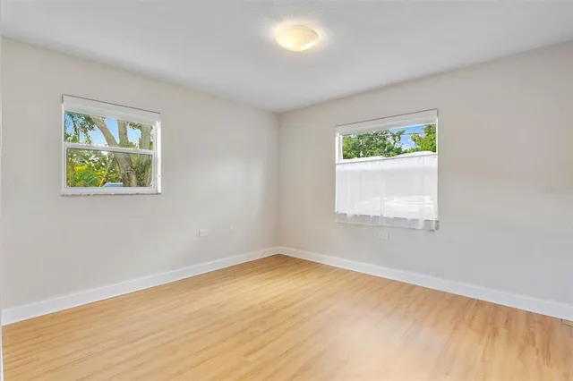 a view of an empty room with a window and wooden floor