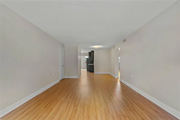 a view of a big room with wooden floor and windows