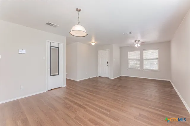 a view of an empty room with window and wooden floor