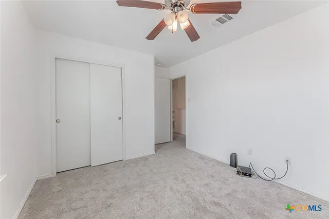 an empty room with closet and a chandelier fan