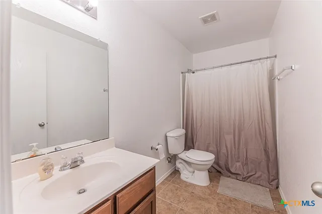 a bathroom with a sink a toilet and shower curtain