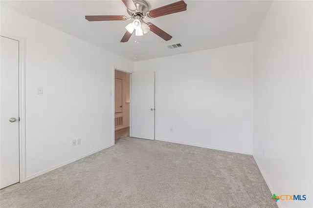 an empty room with a chandelier fan and closet