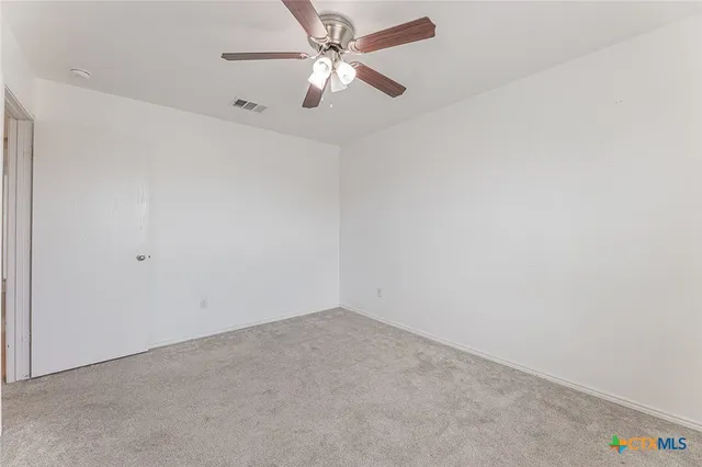 an empty room with a window and a fan
