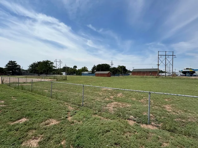 a view of a field with grass and trees in the background