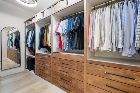 a view of walk in closet with clothes and shoes