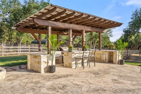 a view of a patio with a table and chairs under an umbrella with a small yard