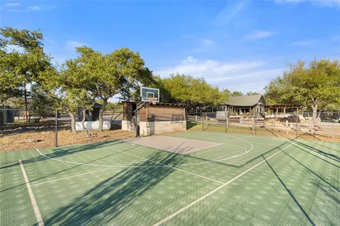 a view of a tennis ground with large trees