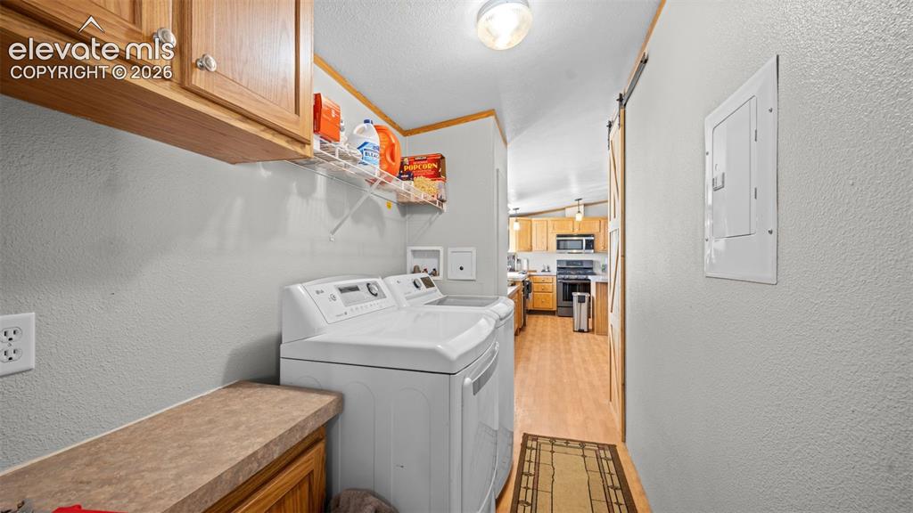 33975 Highway 94 Yoder, CO 80864 - Photo 14 of 40 Dedicated laundry area featuring overhead cabinetry, a built-in countertop, wire shelving, and wood-finish flooring