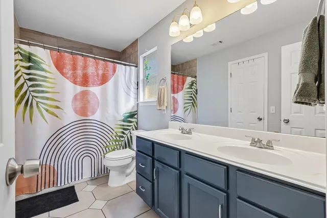 a bathroom with a sink a mirror a toilet and a window