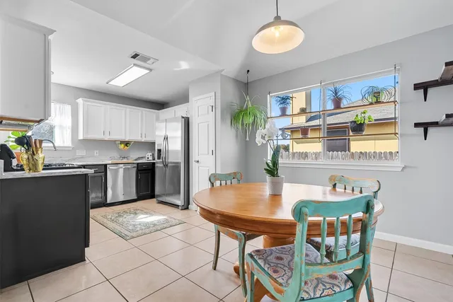 a kitchen with stainless steel appliances granite countertop a stove top oven a sink a dining table and chairs with wooden floor