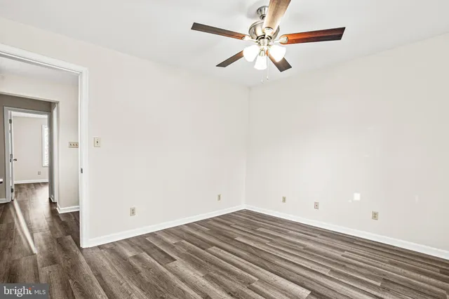 an empty room with wooden floor and fan