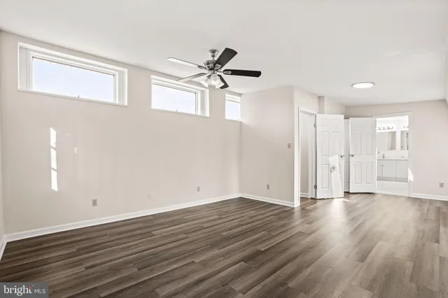 a view of empty room with wooden floor and fan