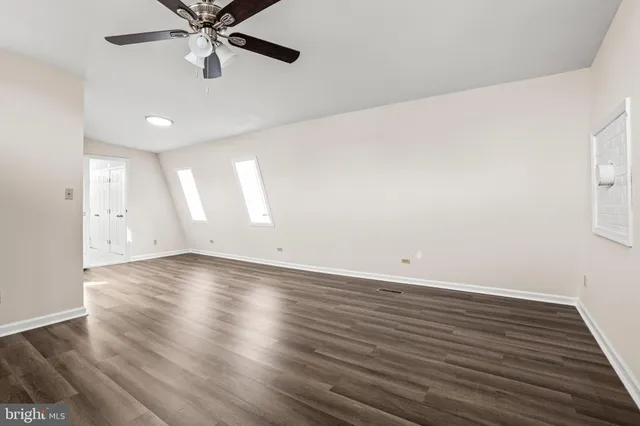 an empty room with wooden floor fan and windows