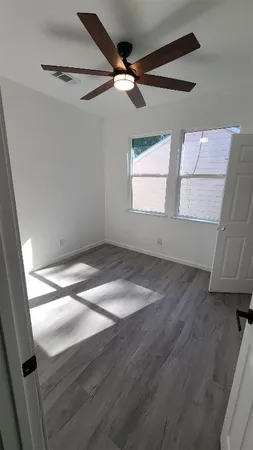 an empty room with wooden floor and windows