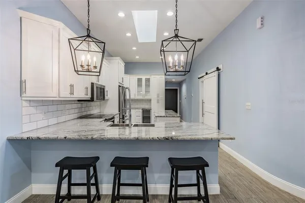 a kitchen with stainless steel appliances kitchen island granite countertop a table chairs in it and wooden floors