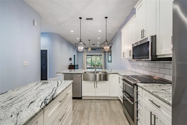 a kitchen with stainless steel appliances granite countertop a sink stove and refrigerator