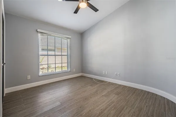an empty room with wooden floor fan and windows