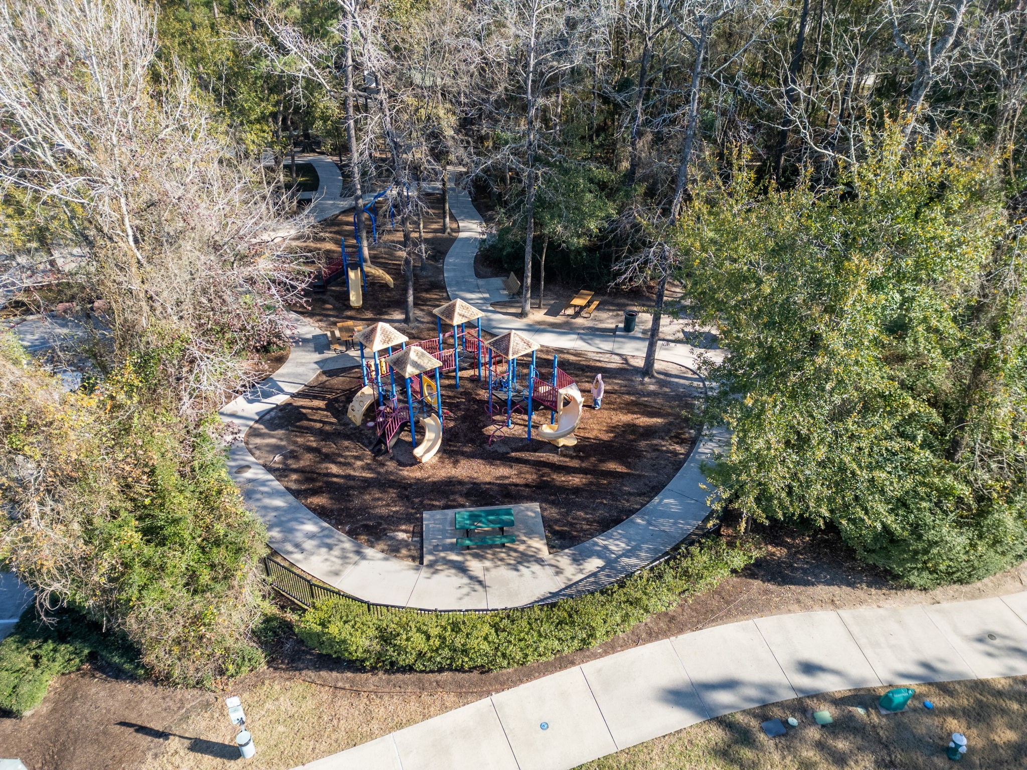 31731 Redbud Blossom Lane Spring, TX 77386 - Photo 37 of 38 This photo showcases a well-maintained playground nestled in a wooded area, featuring slides and climbing structures. It is surrounded by walking paths, benches, and lush greenery, offering a peaceful and family-friendly environment.