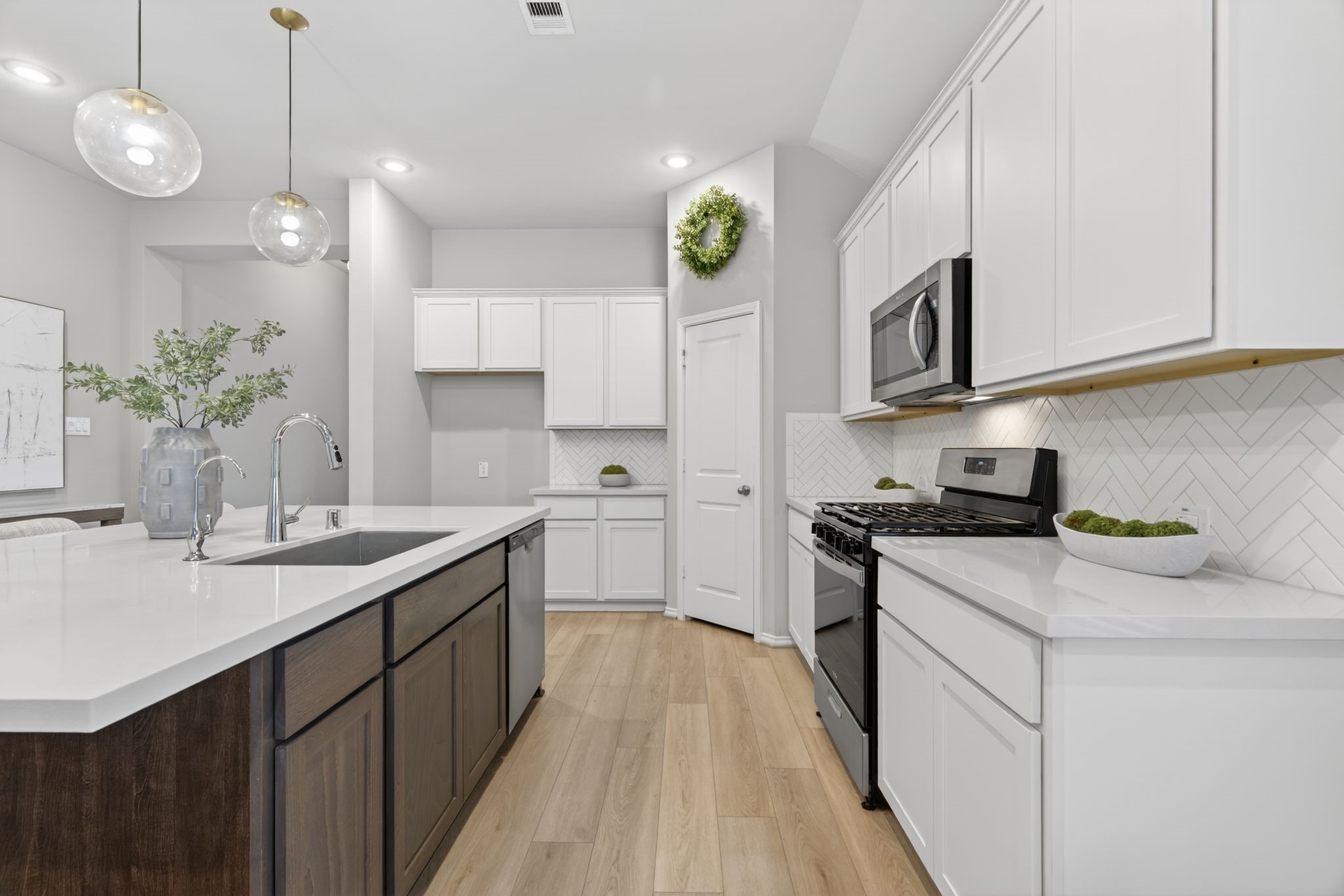 31731 Redbud Blossom Lane Spring, TX 77386 - Photo 10 of 38 This modern kitchen a stylish herringbone backsplash, and stainless steel appliances. The large island with a dark wood base and quartz countertop offers ample space for cooking and entertaining. This spaces adds warmth and elegance for anyone to love.