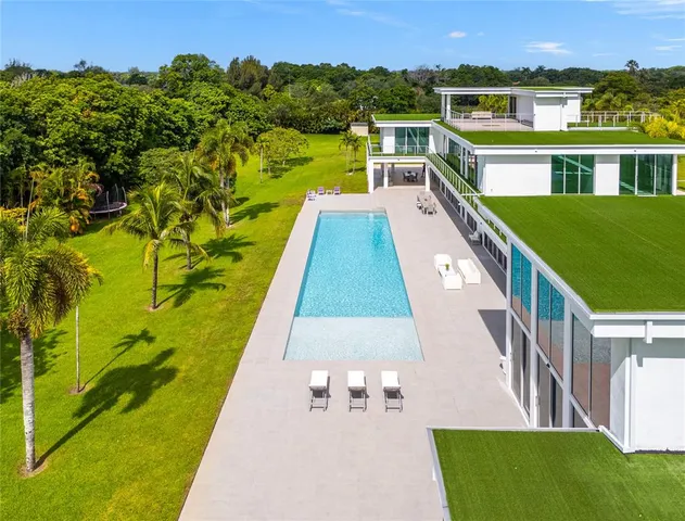 a view of swimming pool with lawn chairs and plants