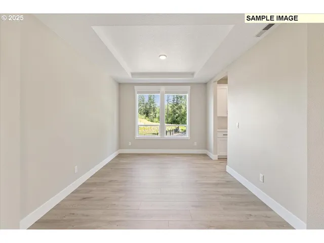 a view of an empty room with wooden floor fireplace and a window