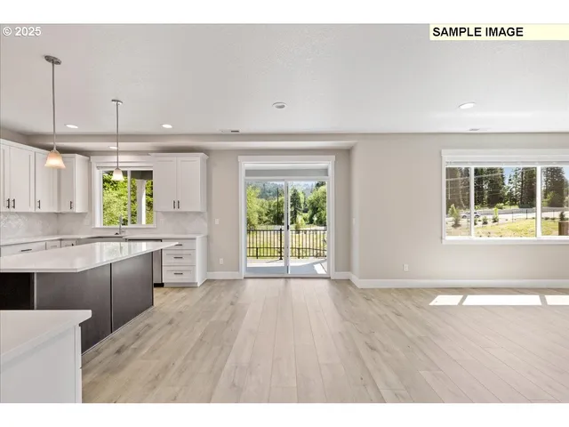 a large white kitchen with a large kitchen island white cabinetry and wooden floor