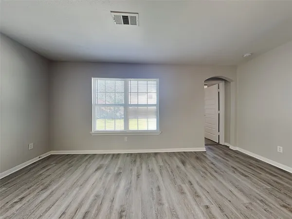 an empty room with wooden floor and windows