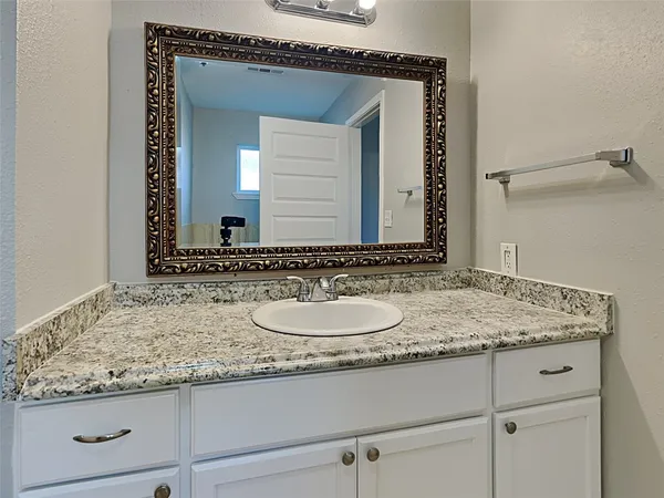 a bathroom with a granite countertop sink and a mirror