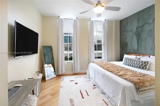 a bedroom with a bed a flat screen tv and a chandelier