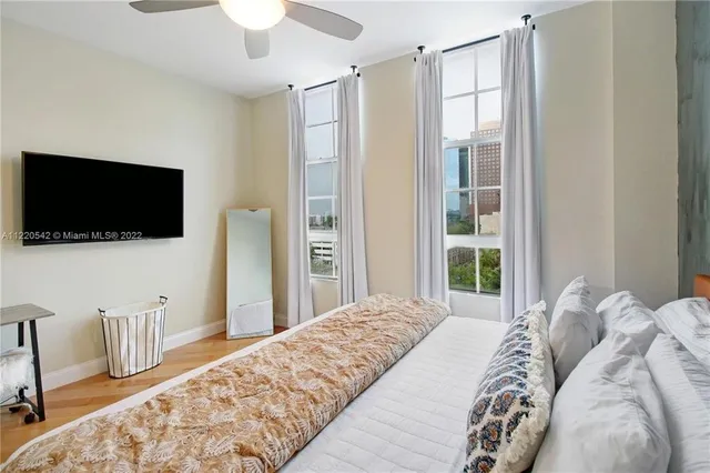 a bedroom with a bed tv and a window