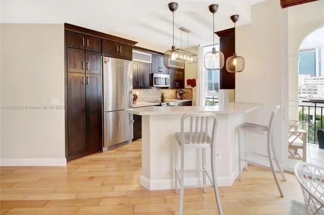 a kitchen with stainless steel appliances kitchen island granite countertop a refrigerator a stove and a sink