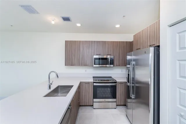 a kitchen with stainless steel appliances a refrigerator sink and microwave