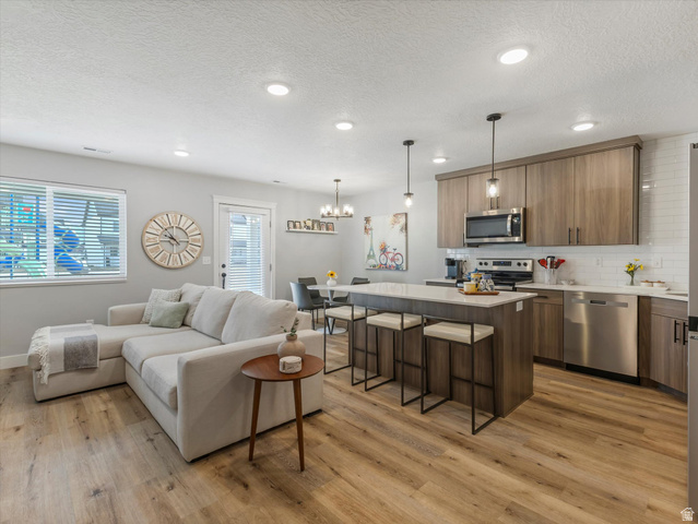 3047 Old Emigrant Road, Unit C Syracuse, UT 84075 - Photo 3 of 20 Living room with light wood finished floors, a textured ceiling, and hanging lights
