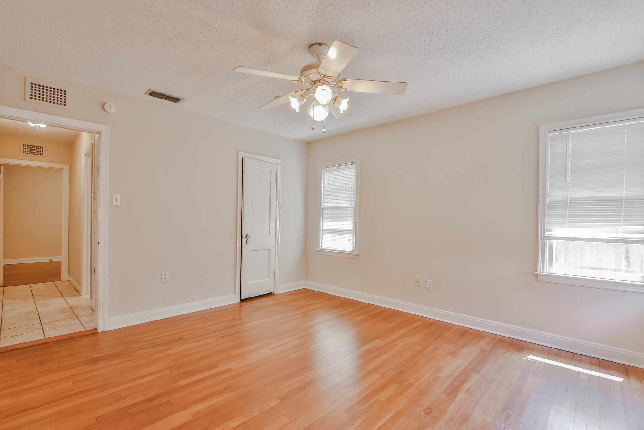 2715 29th Street Lubbock, TX 79410 - Photo 18 of 35 an empty room with wooden floor chandelier fan and windows