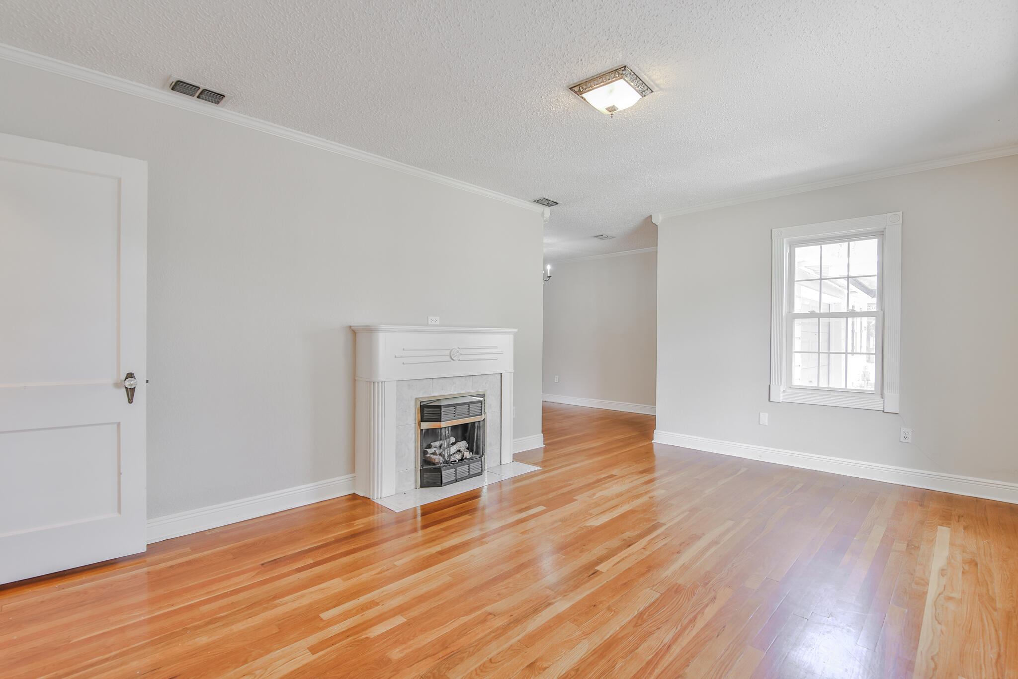 2715 29th Street Lubbock, TX 79410 - Photo 4 of 35 an empty room with wooden floor fireplace and windows