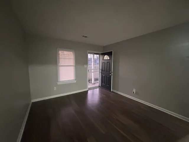 a view of an empty room with wooden floor and a window