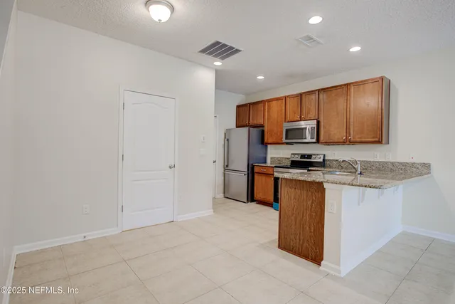 a kitchen with stainless steel appliances granite countertop a stove top oven a sink and a refrigerator