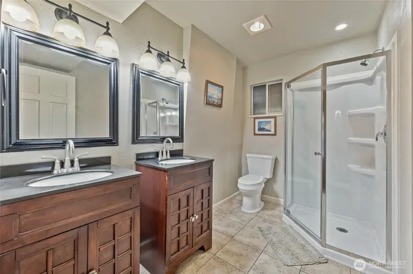 a spacious bathroom with a granite countertop sink toilet a mirror and shower